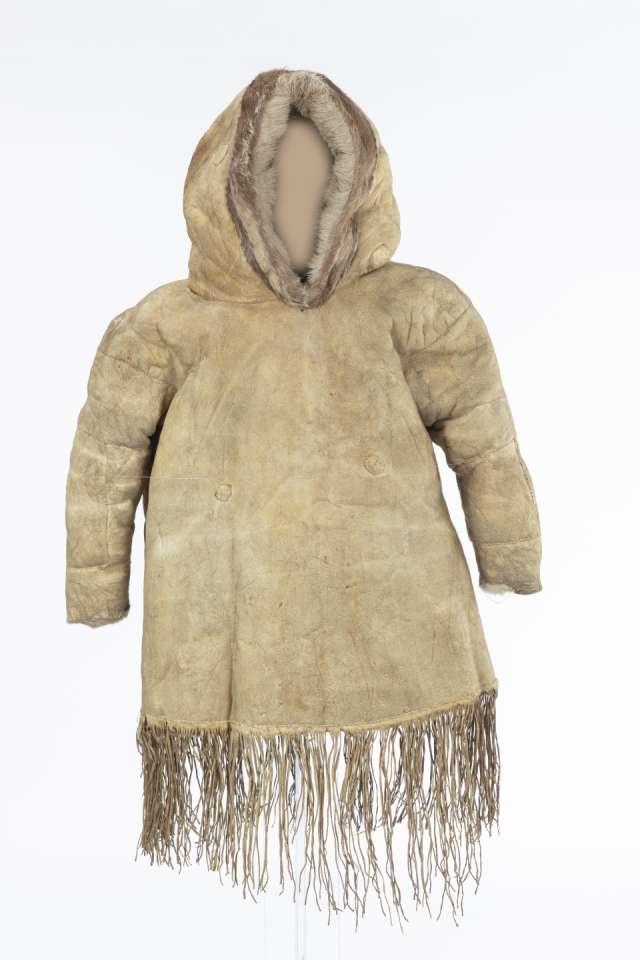 Veste en cuir beige, vue de face, avec le capuchon relevé. Le capuchon est bordé de fourrure brune. Des franges ornent le bas de la veste.