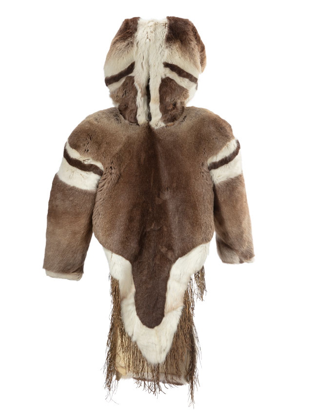 Manteau en fourrure brune, vu de face, avec le capuchon relevé. Des bandes de fourrure claires et foncées sont visibles sur les épaules et les côtés du capuchon. Le pan avant du manteau, plus court et arrondi que l’arrière, est bordé de fourrure blanche et orné de franges.