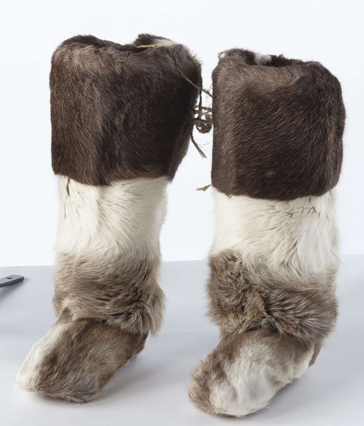 Two long boots. They're covered with thick, alternating dark brown and white fur over their entirety.